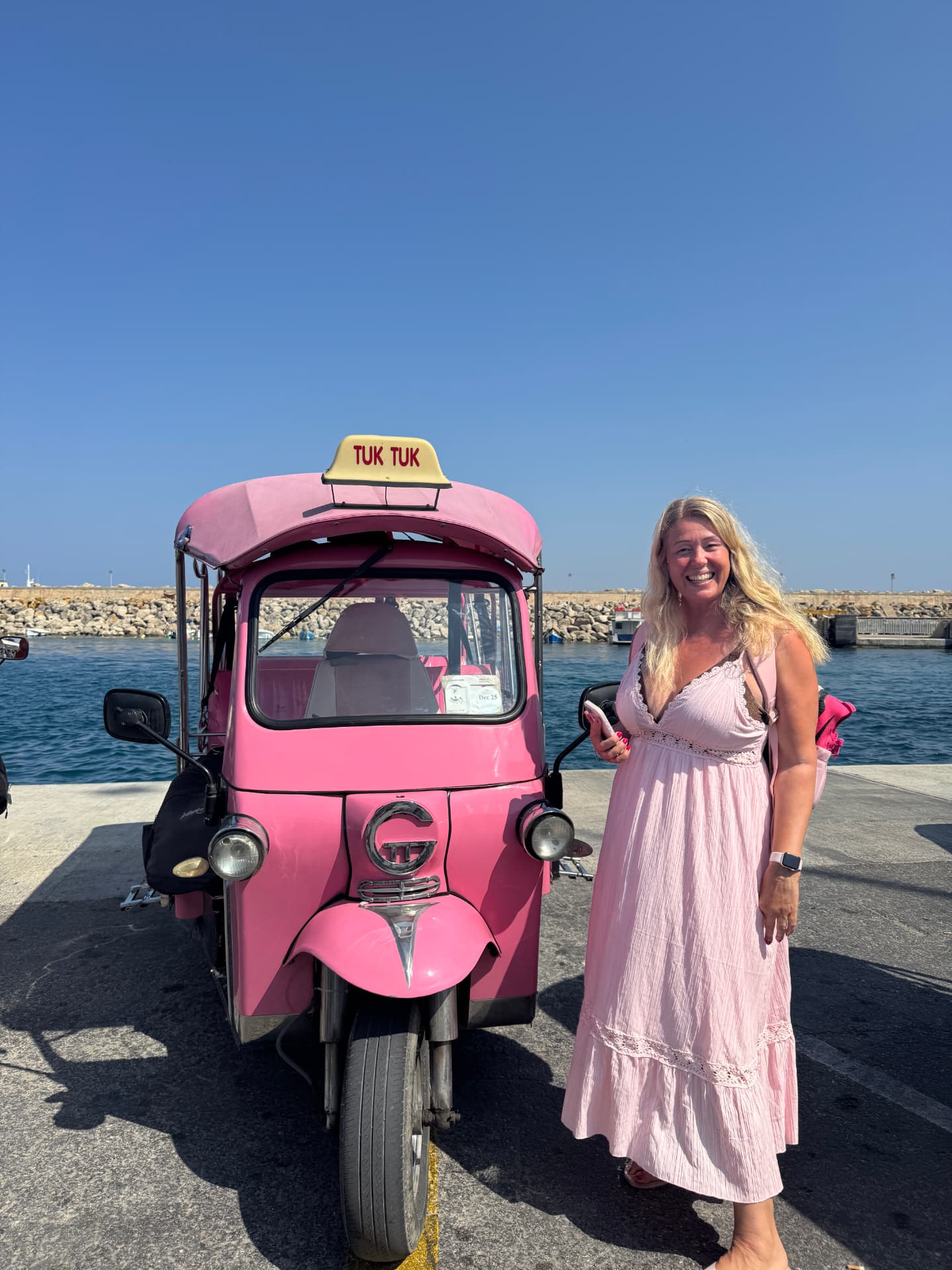 Mette i rosa kjole ved siden af en pink tuktuk ved havnen